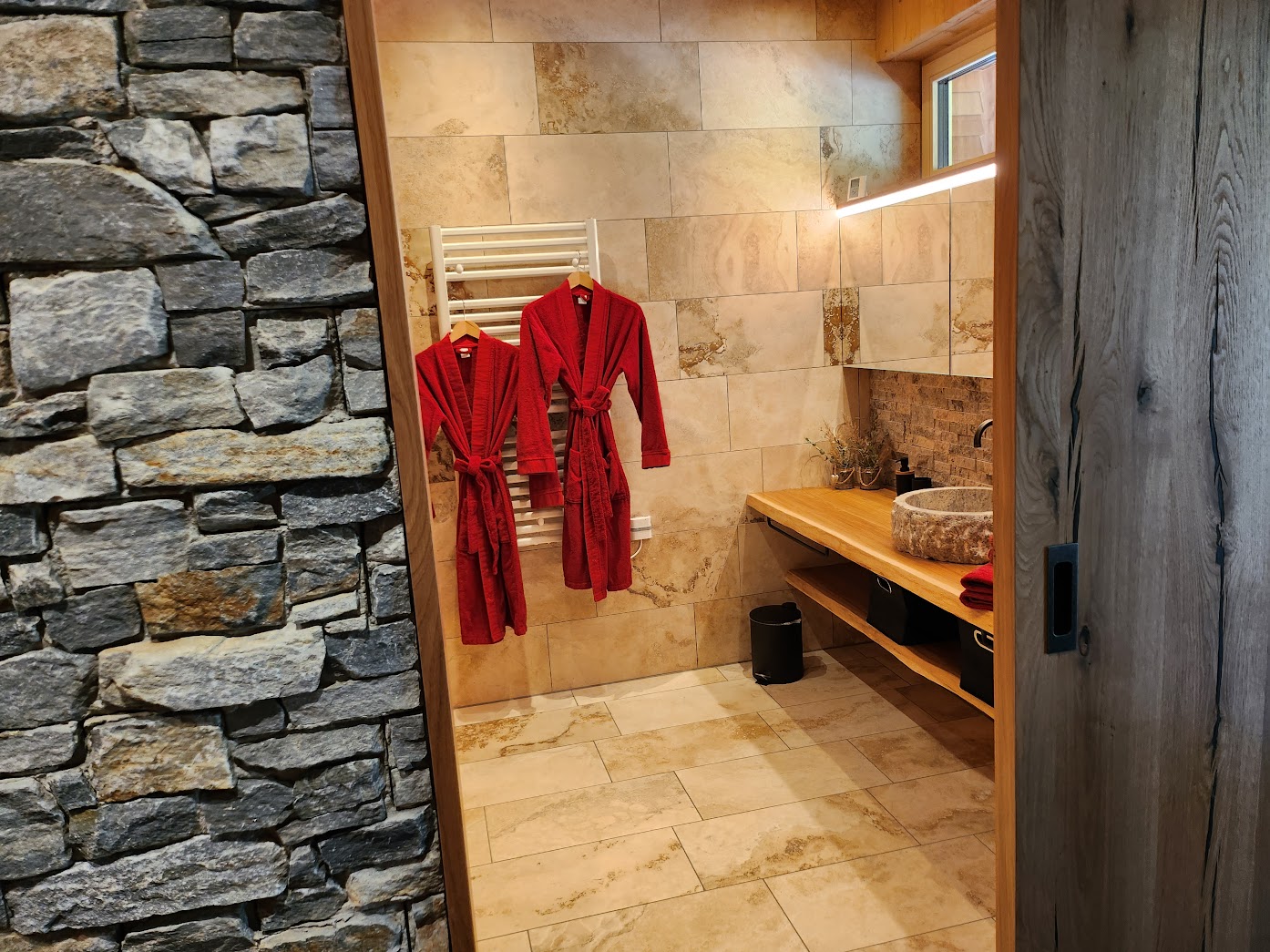Badezimmer in Hugos mit Natursteinwand, Bademantel und Steinwaschbecken