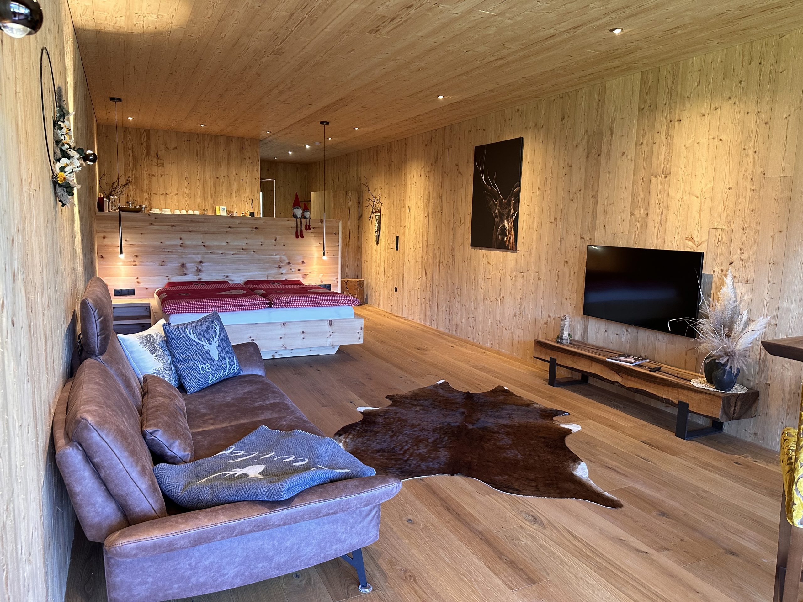 Wohn- und Schlafbereich in Hugos mit Sofa, Zirbenbett und Fernseher