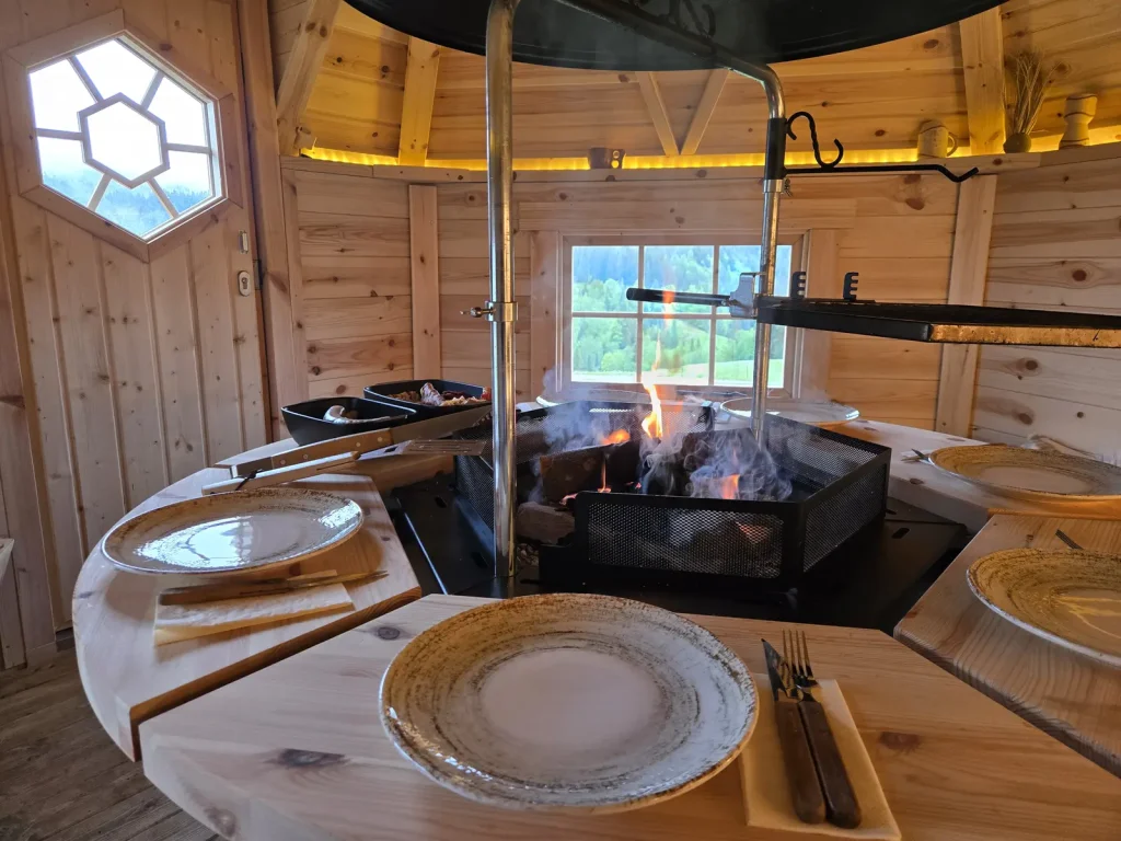 Grillkota mit rundem Tisch und Feuerstelle am Alpenchalet