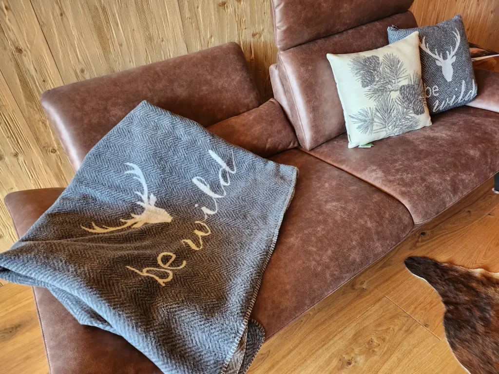 Ledersofa mit Kissen und Decke im Alpenchalet