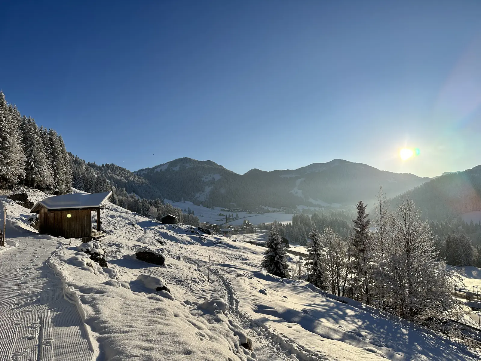 Winterlandschaft mit Hütte und Sonne bei Balderschwang