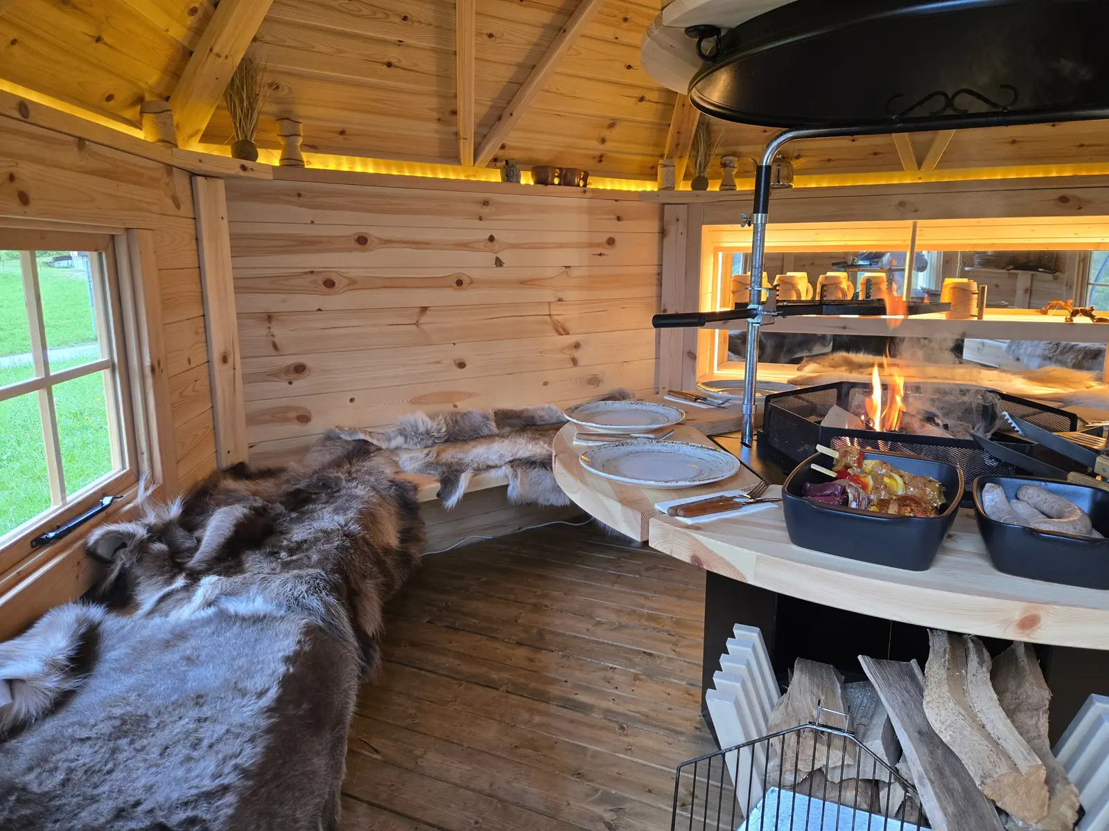 Grillkota von innen mit offenem Feuer und Fellen