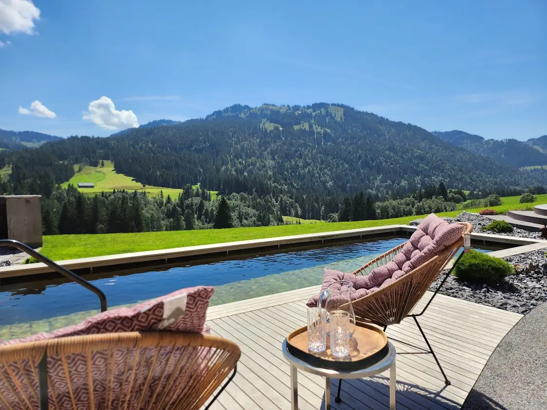 Natur-Pool des Alpenu mit Liegestühlen und Blick auf die Allgäuer Berge