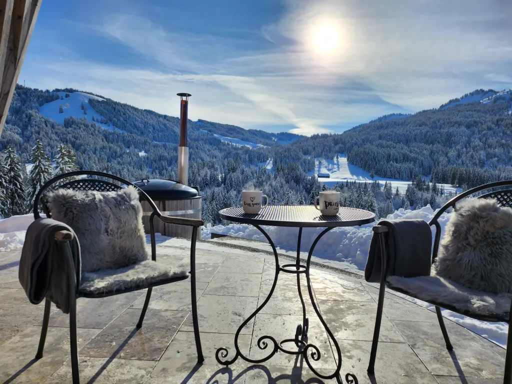 Winterterrasse mit Tisch und Fellen am Chalet in den Alpen